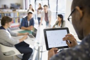 Man Typing on iPad in Front of Group of People