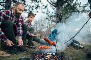 Two Men Roasting Food at a Campfire