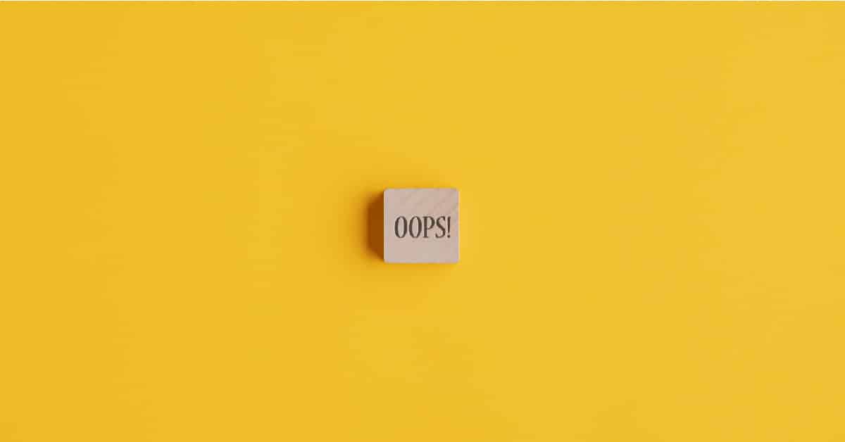 Wooden tile with word "oops" against a yellow background.