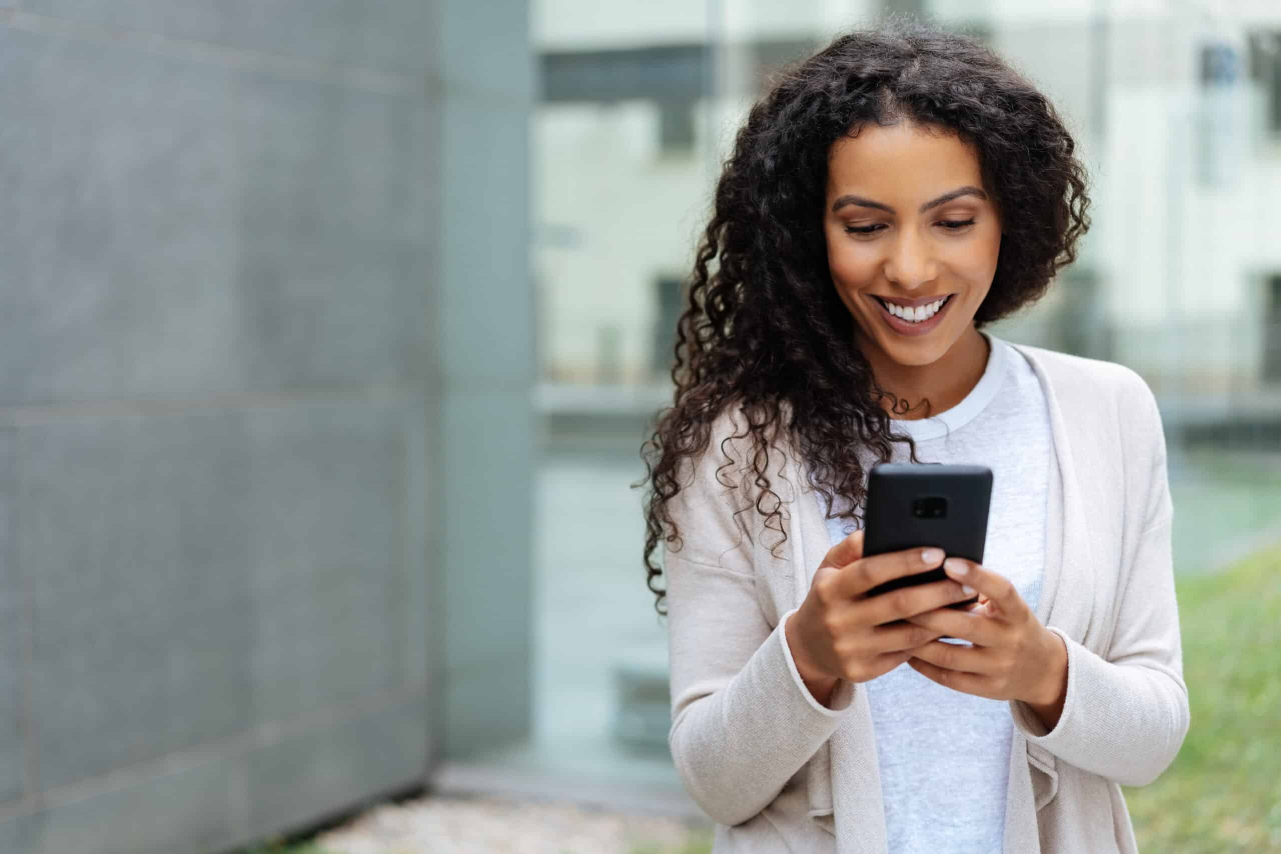 Young woman walking through town using a mobile phone