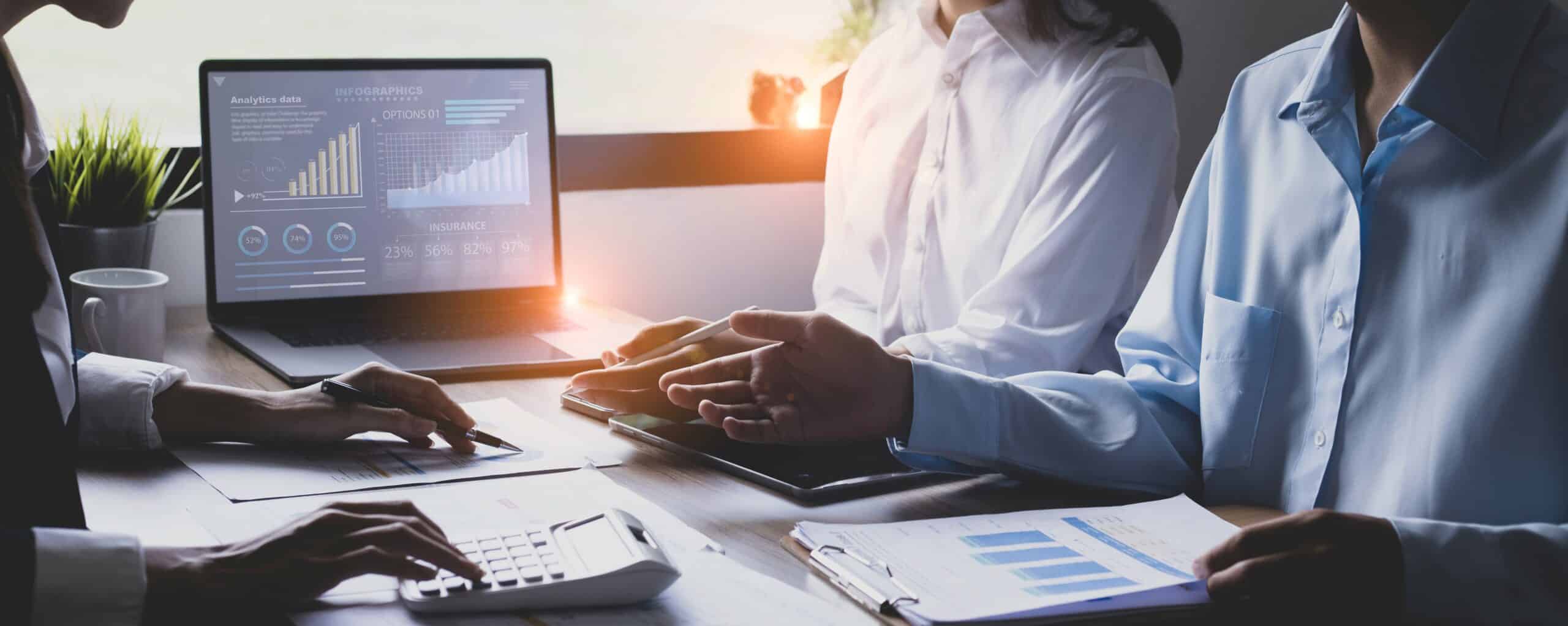 three people in meeting with laptop and charts