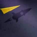 paper airplane with the shadow of a rocket ship