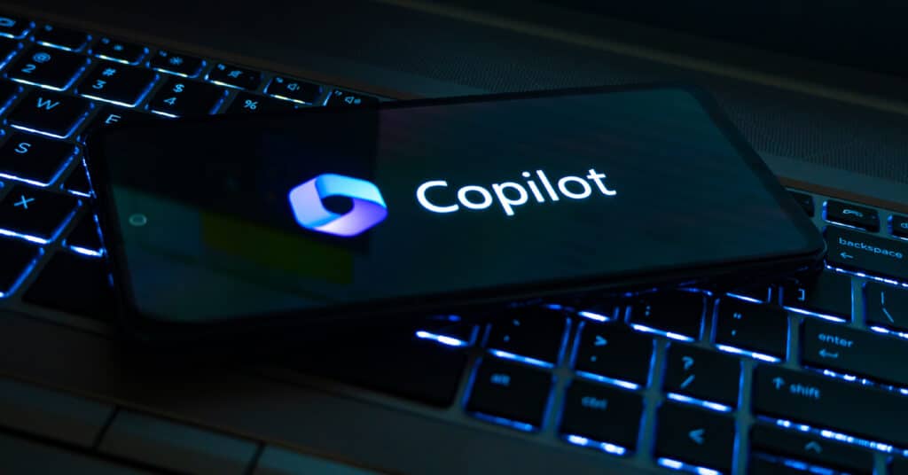 Cell phone laying on laptop displaying the Microsoft Copilot logo