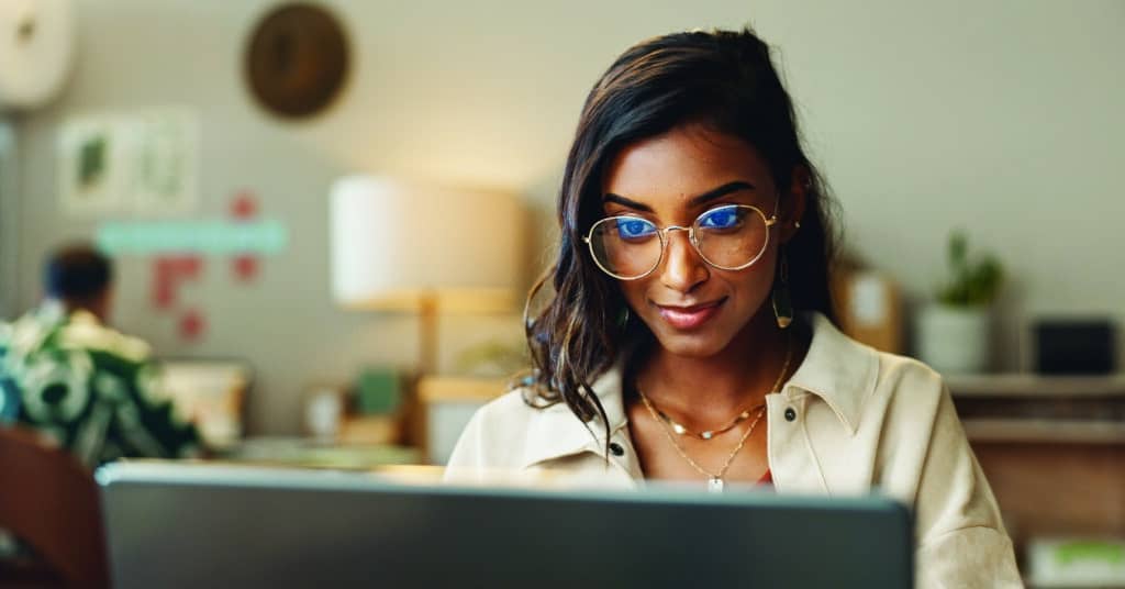 Sales woman smiling and creating a sales order on her laptop.